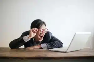 man with glasses screaming at his computer